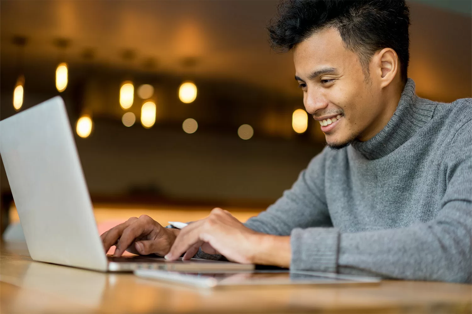 Student sitting in front of a laptop and smiling.
